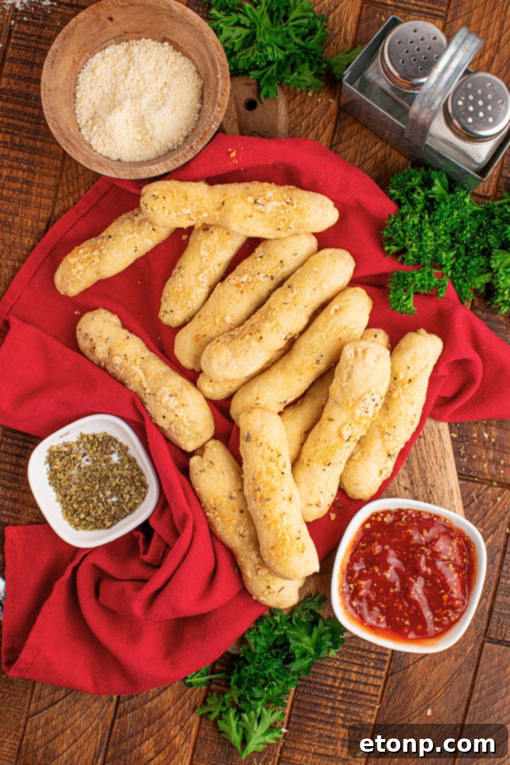 Easy Buttery Garlic Parmesan Breadsticks Two Ingredients 23 An overhead view of a delicious breadstick garnished with sauce, Parmesan cheese, oregano, and other seasonings.