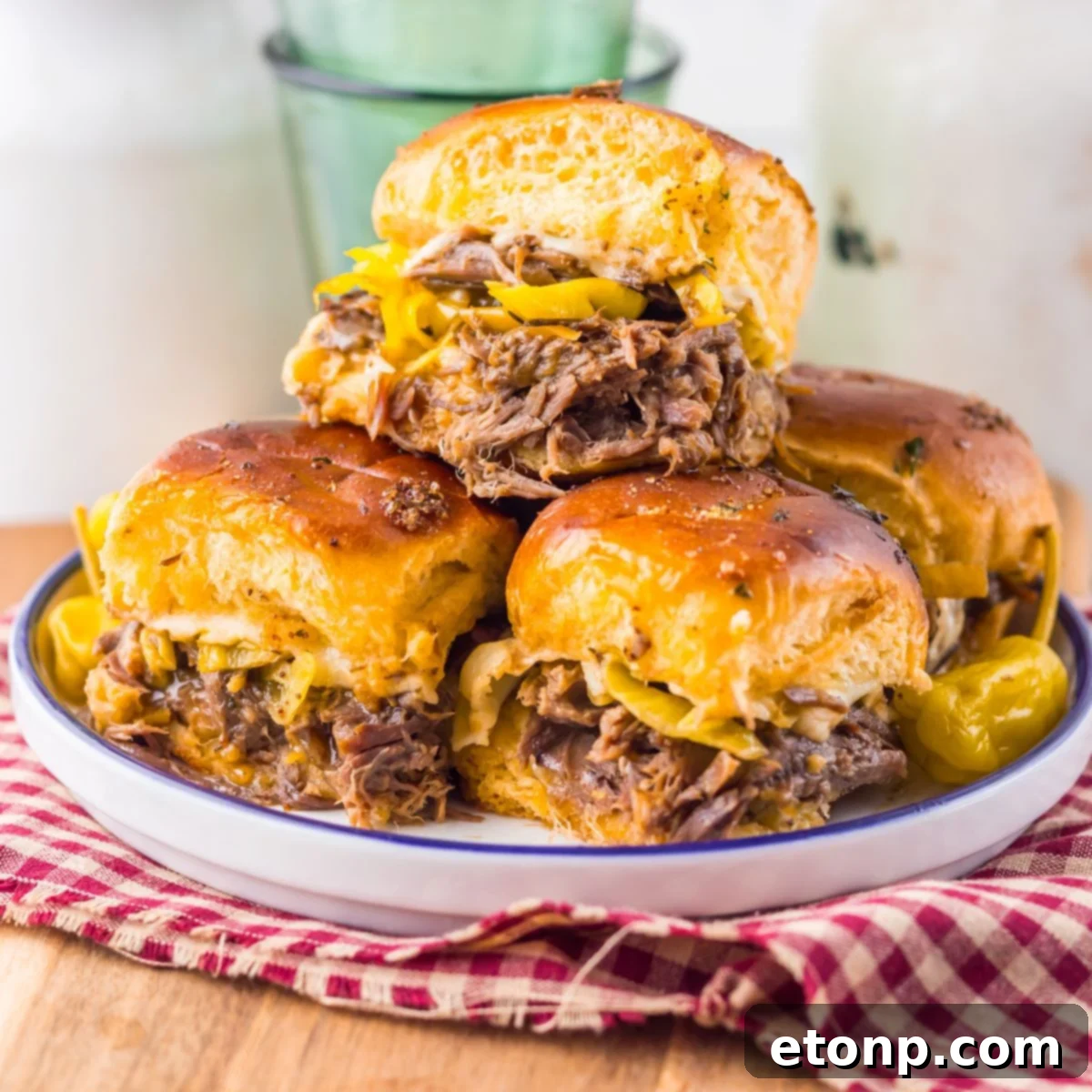 Slow Cooker Mississippi Pot Roast Sliders stacked on a plate sitting on a table 