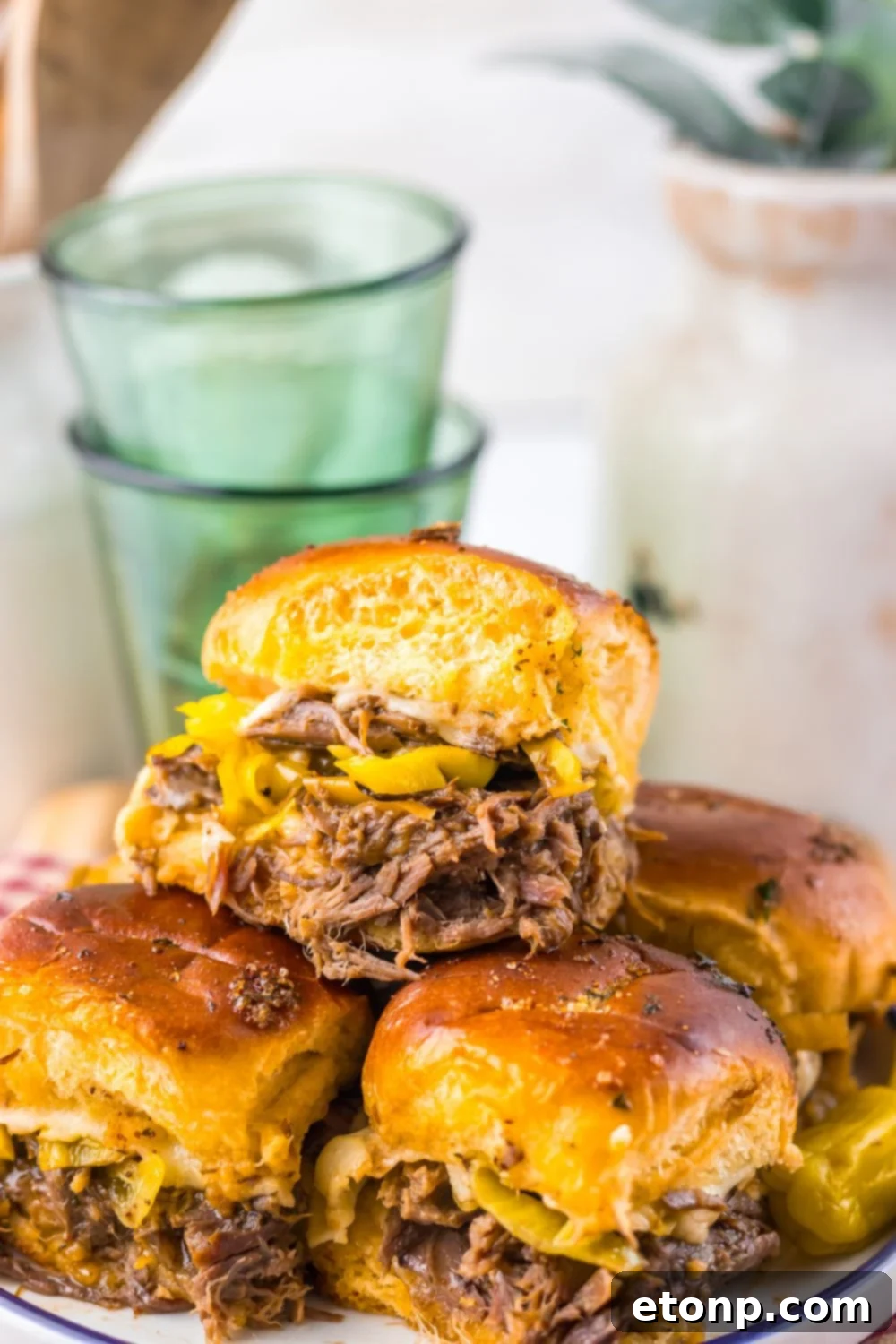 Slow Cooker Mississippi Pot Roast Sliders stacked on a plate with a close up of sliders on table 