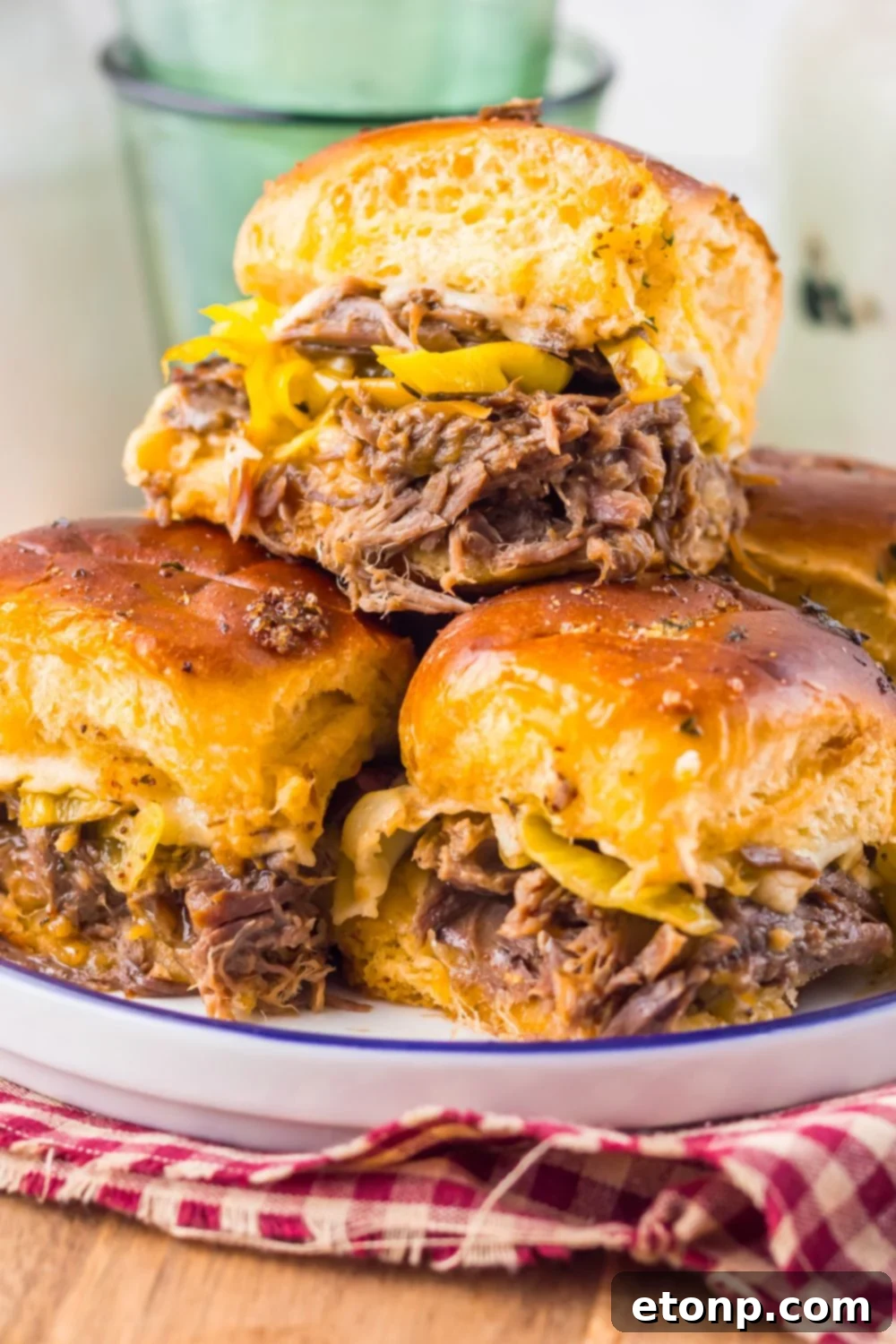 close up of Slow Cooker Mississippi Pot Roast Sliders on a plate with a red checkered towel under it 