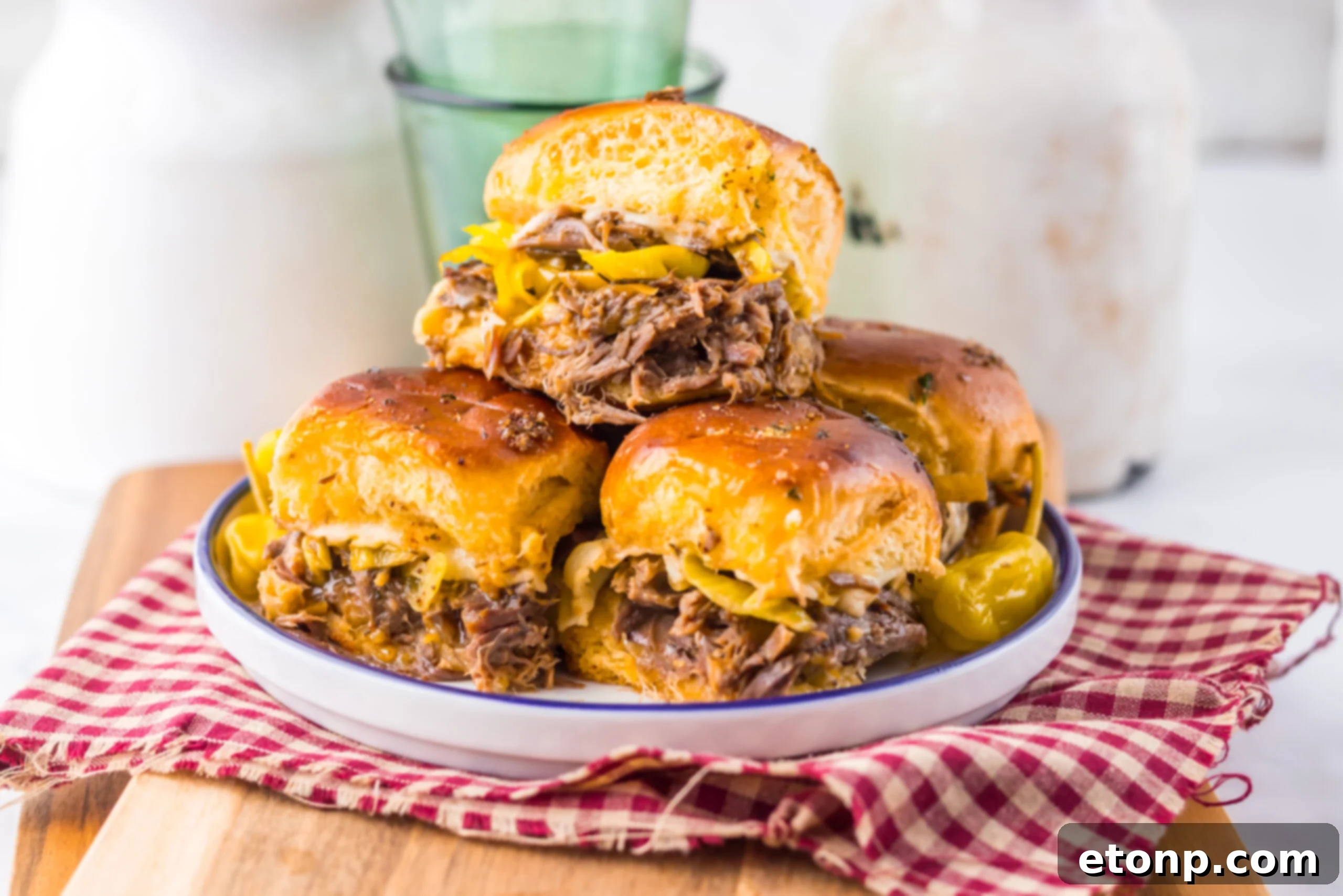 close up of Slow Cooker Mississippi Pot Roast Sliders on a plate with a red checkered towel under it 