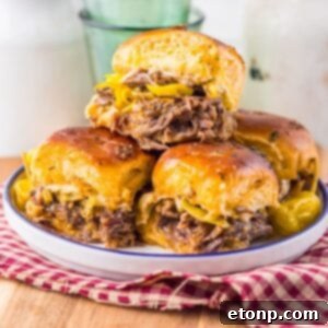 Slow Cooker Mississippi Pot Roast Sliders stacked on a plate sitting on a table