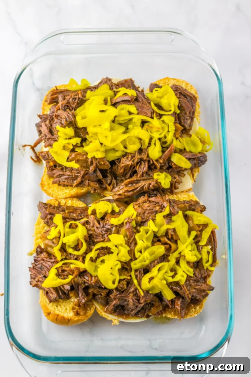 overhead look of pan with meat and peppers on top of slider buns 