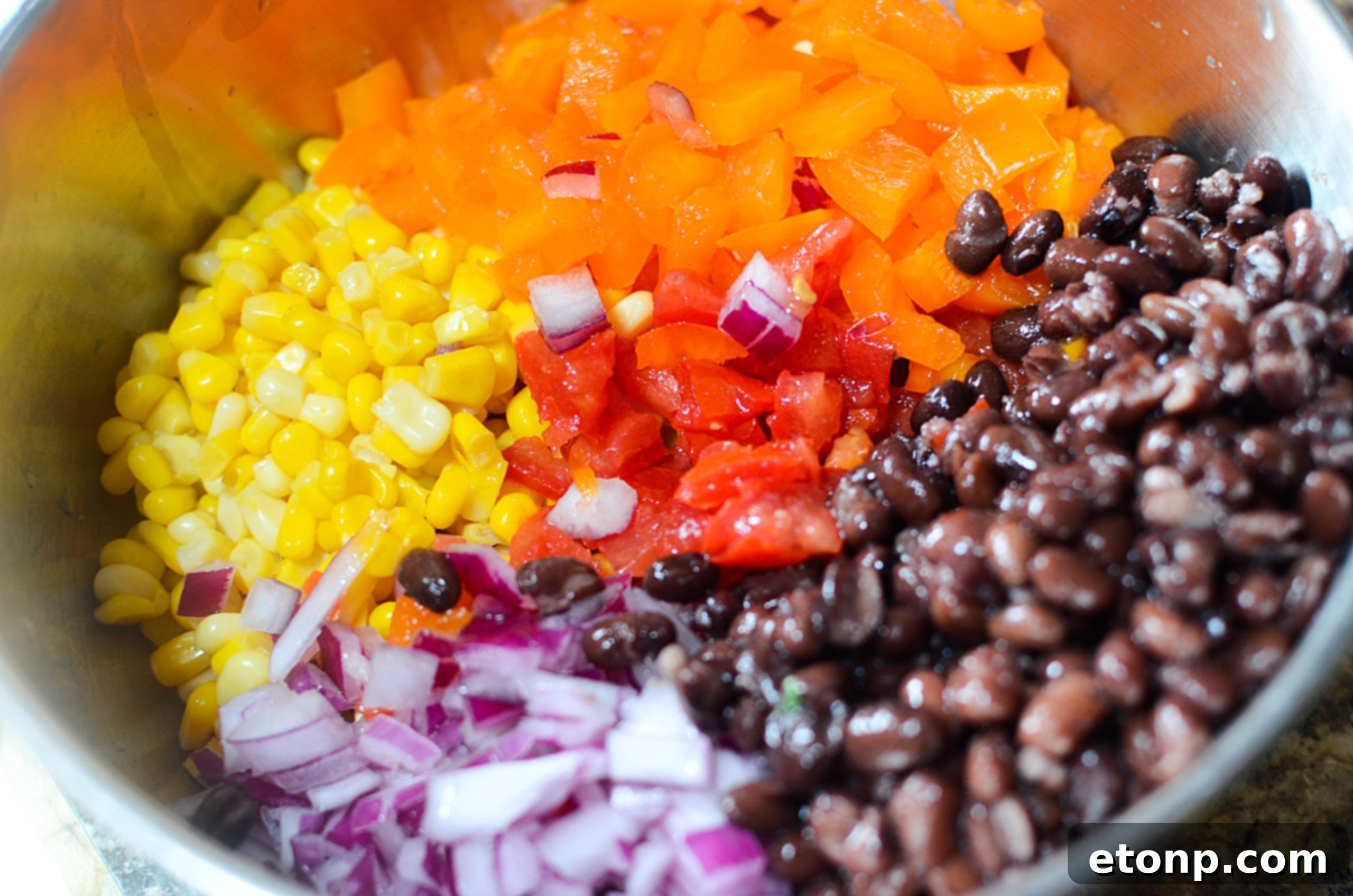 Close-up of Cowboy Caviar with tortilla chips on a rustic wooden board, perfect for dipping.