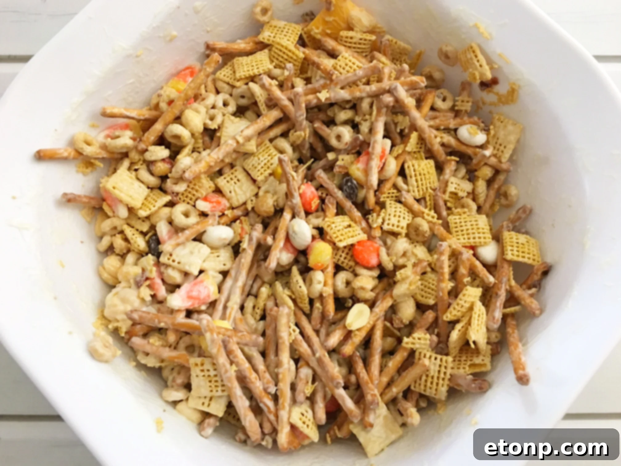 A large mixing bowl filled with various ingredients for Fall Harvest Crack, including pretzels, cereals, and nuts, before being coated.