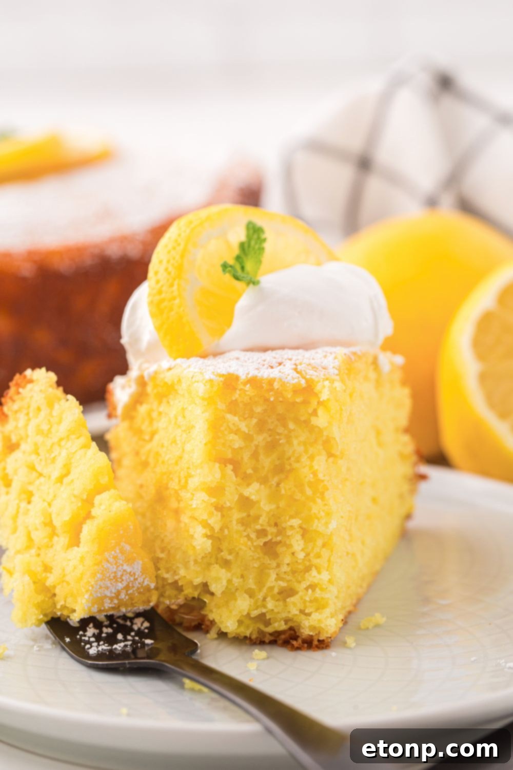 Effortless Italian Lemon Ricotta Cake: Light and Lemony Perfection 11 A close-up view of a slice of Italian Lemon Ricotta Cake on a plate, with a bite playfully taken out, highlighting its fluffy and rich texture.
