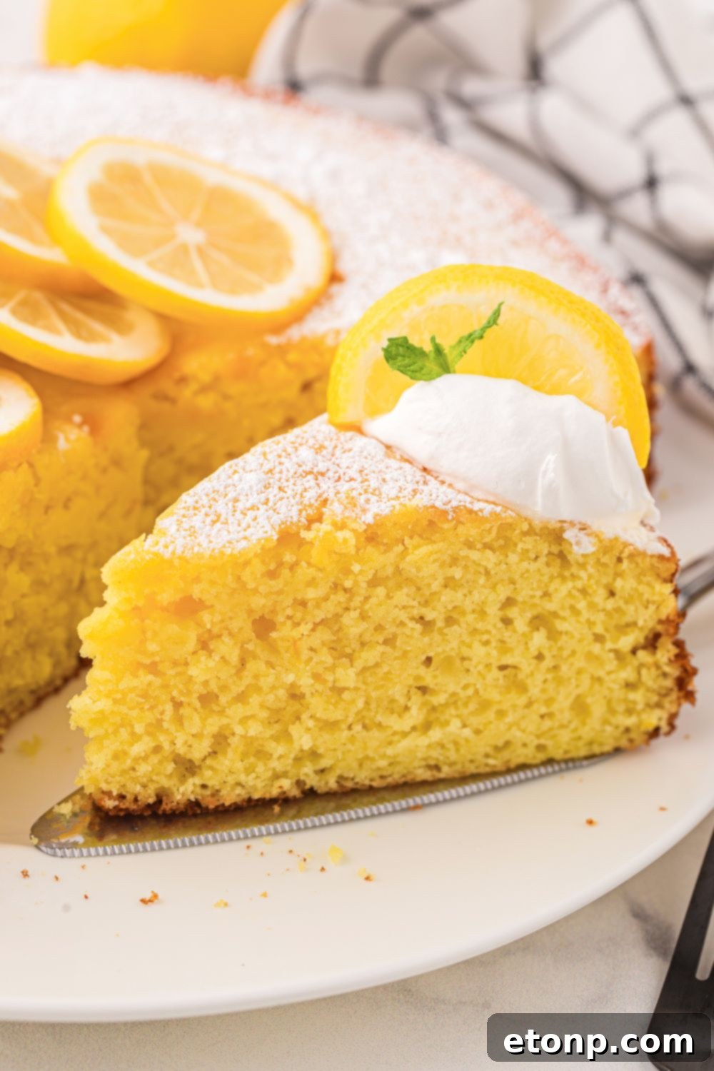 Effortless Italian Lemon Ricotta Cake: Light and Lemony Perfection 16 A full Italian Lemon Ricotta Cake on a plate with one slice neatly removed, showcasing its appealing texture and readiness for enjoyment.