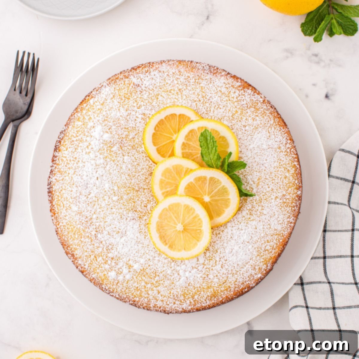 Effortless Italian Lemon Ricotta Cake: Light and Lemony Perfection 3 The full Italian Lemon Ricotta Cake sits elegantly on a table, garnished with fresh lemon slices and delicate mint leaves, ready to be served.