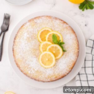 Effortless Italian Lemon Ricotta Cake: Light and Lemony Perfection 24 Lemon Ricotta Cake on table with some fresh lemons on top with some mint leaves to side