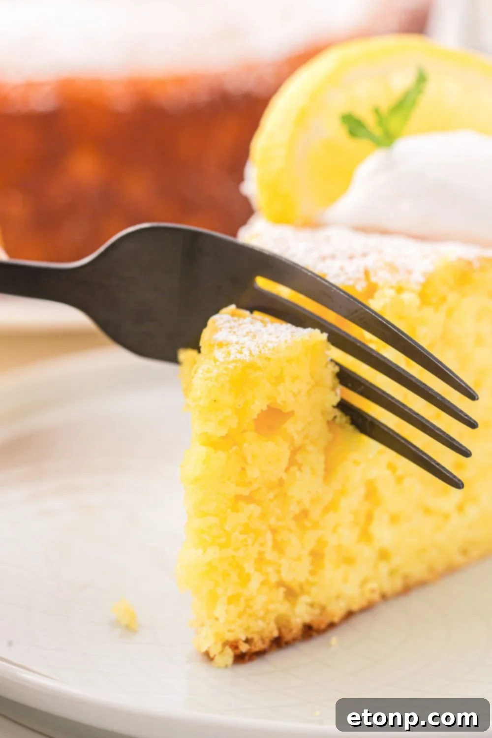 Effortless Italian Lemon Ricotta Cake: Light and Lemony Perfection 4 A close-up shot of a fork gently cutting into a slice of Italian Lemon Ricotta Cake, showcasing its incredibly moist and tender texture.