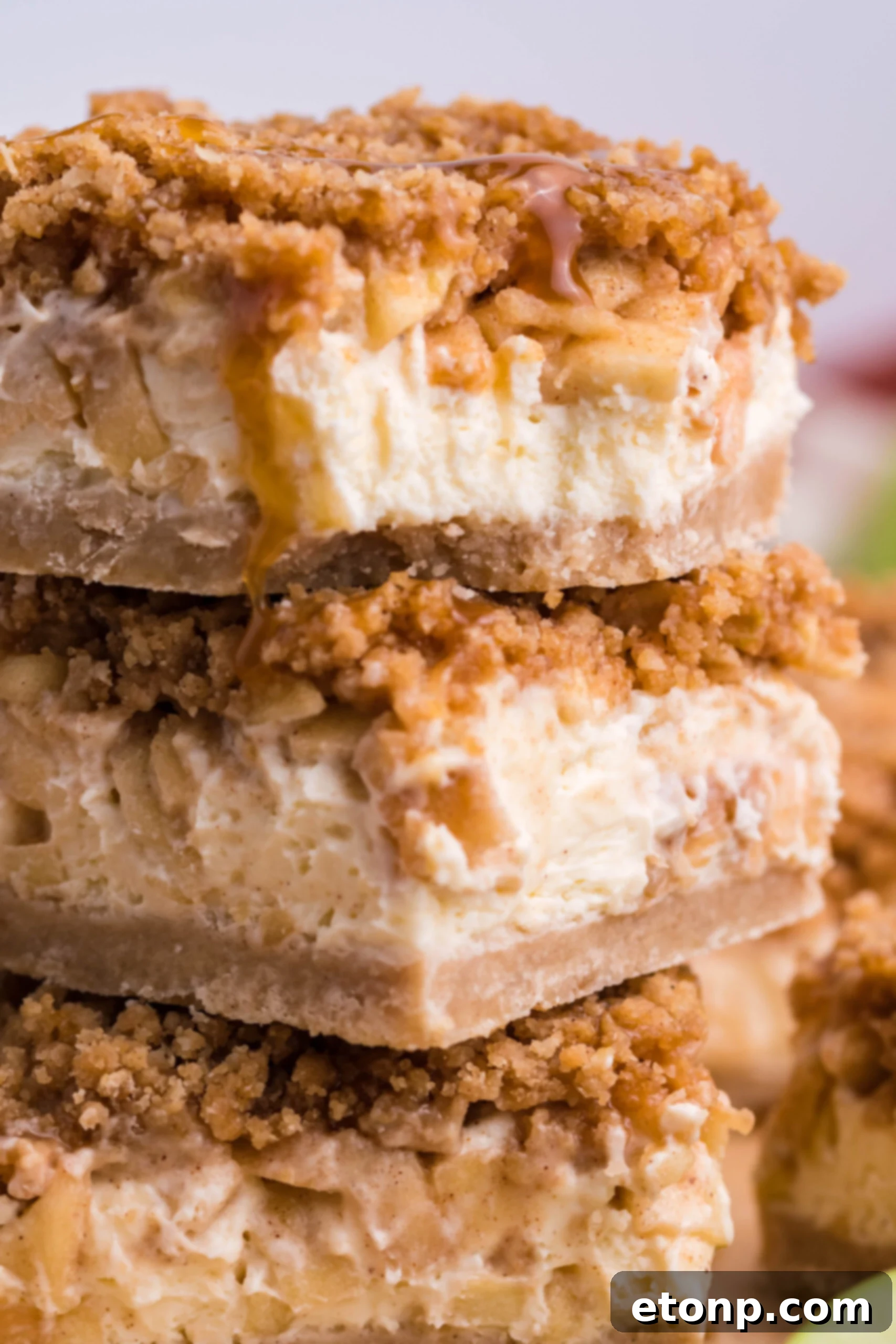 Caramel Apple Cheesecake Bars sliced and stacked on top of one another on a table