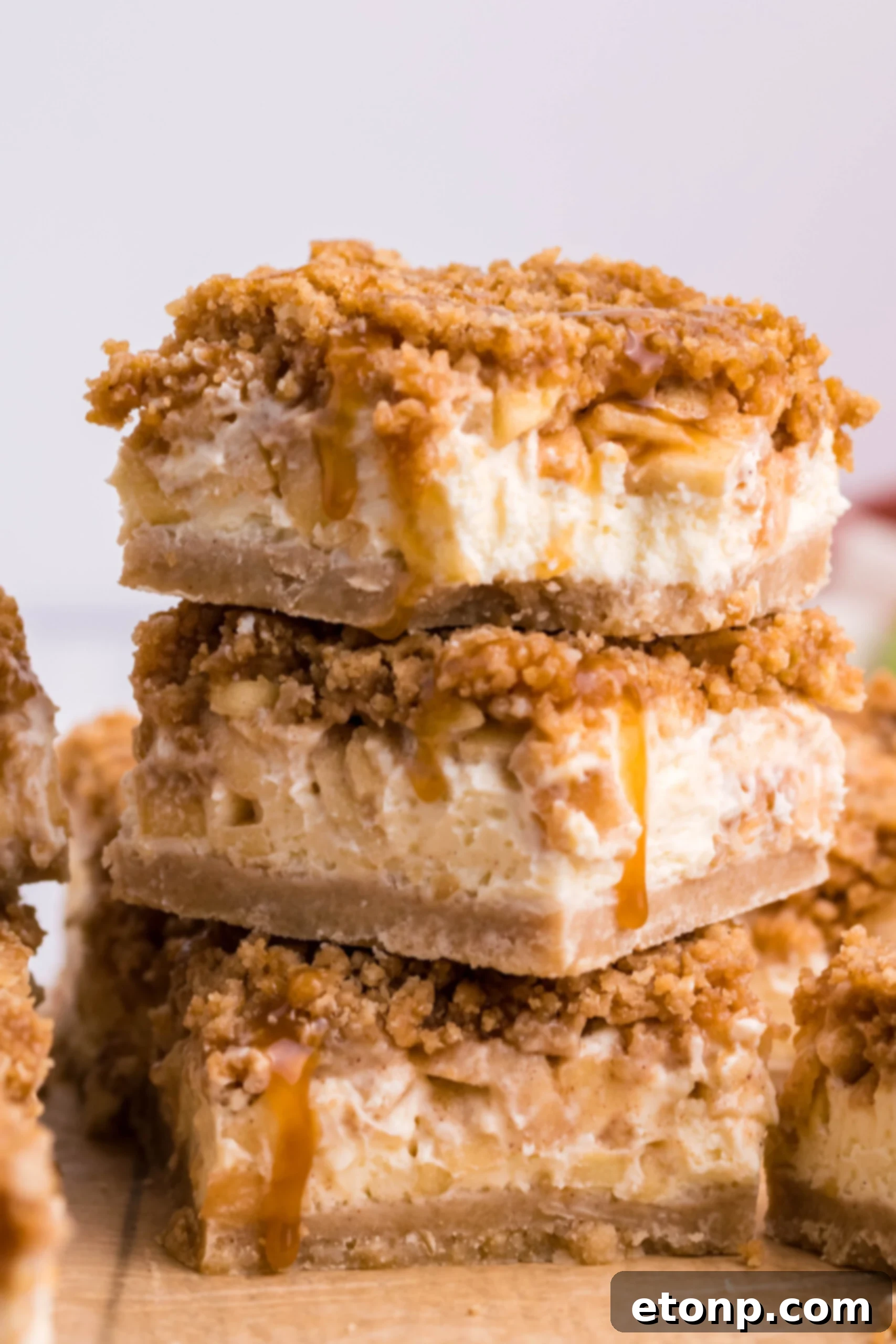 Stack of three Caramel Apple Cheesecake Bars sliced on a table