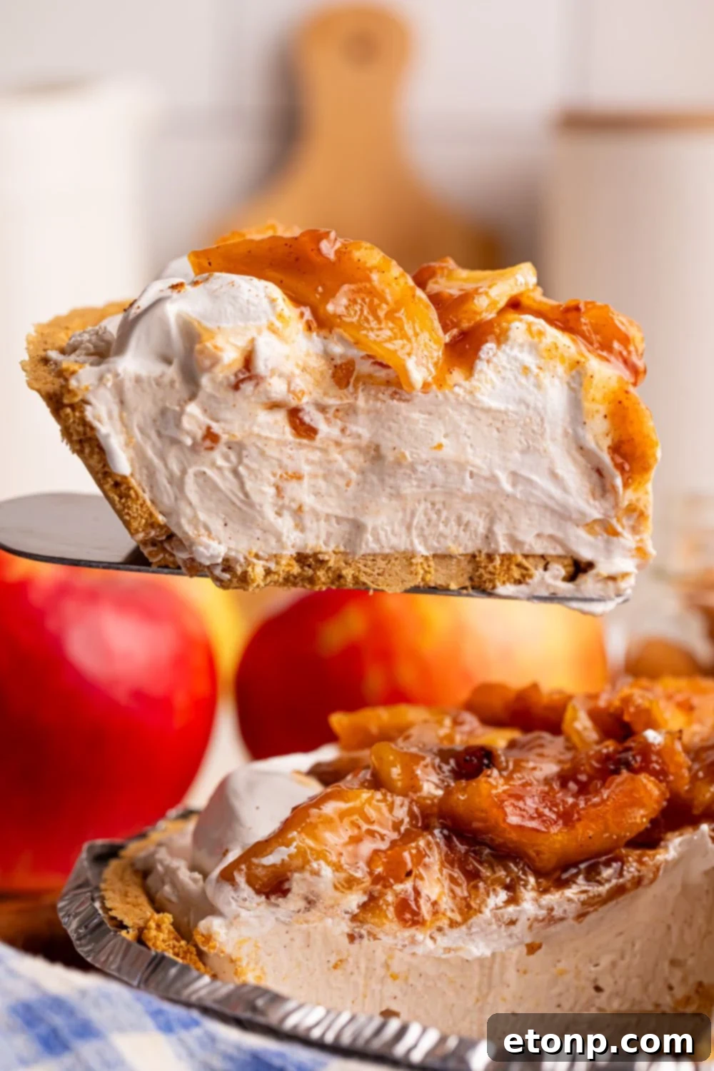 spatula with No Bake Apple Cheesecake pie slice on it above the pie plate 