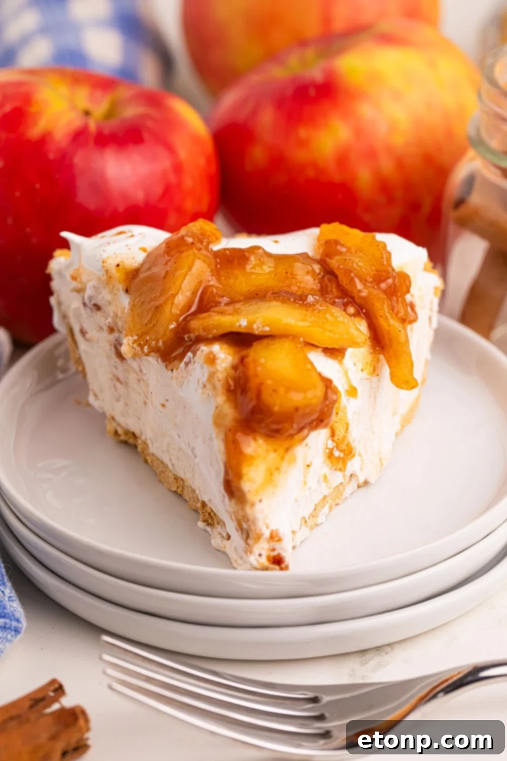 No Bake Apple Cheesecake pie on plates with fresh apples behind it on table 