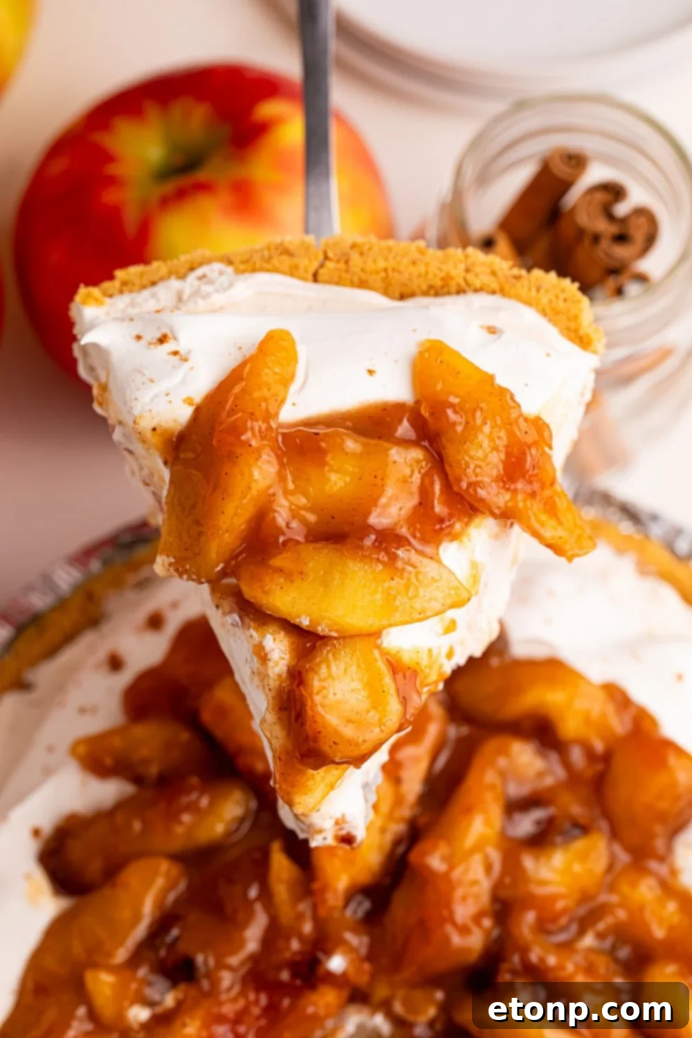No Bake Apple Cheesecake pie on table with a slice coming out of pie plate 