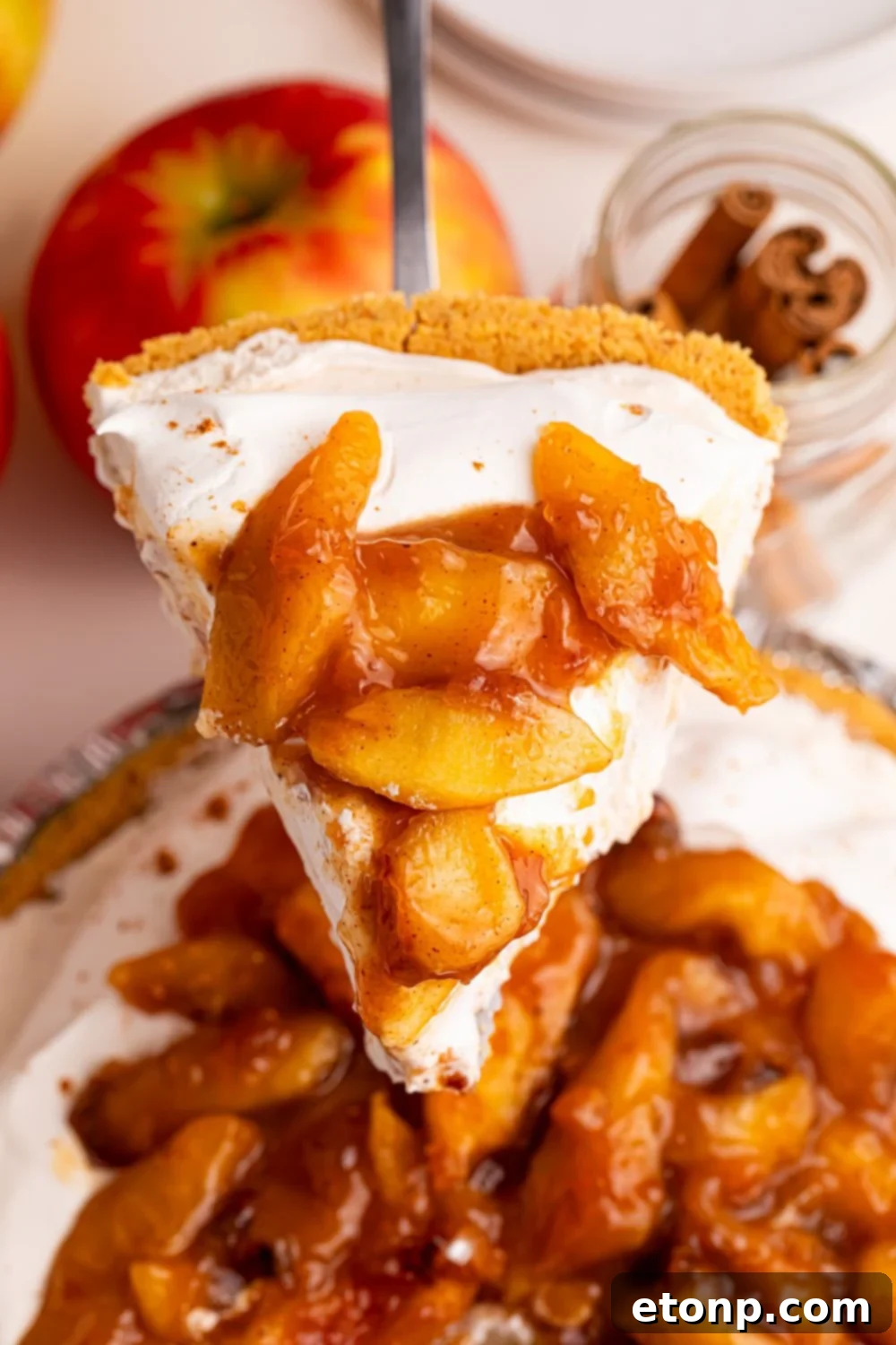 slice of No Bake Apple Cheesecake pie being lifted out of the pie plate on table 
