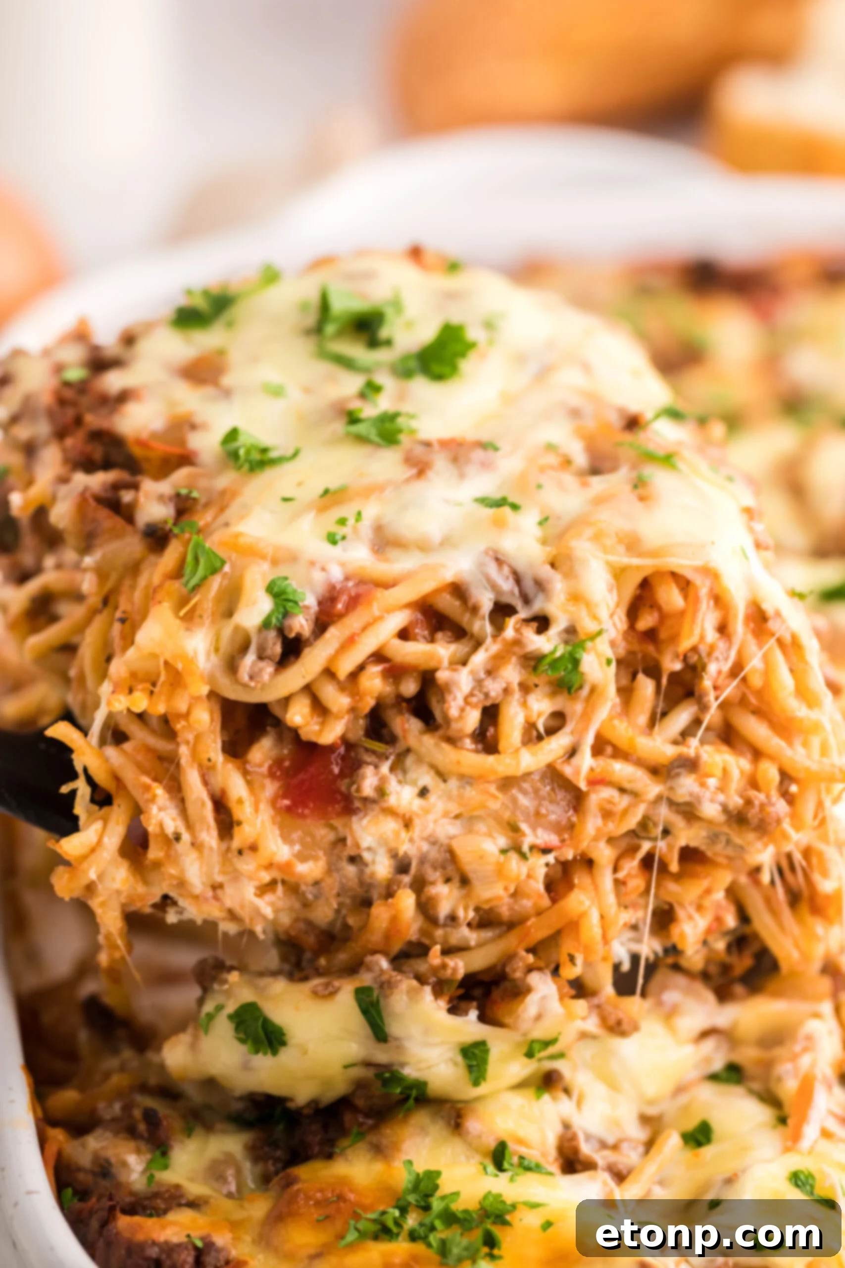 Million Dollar Spaghetti Casserole in a pan with a spatula lifting up a slice 