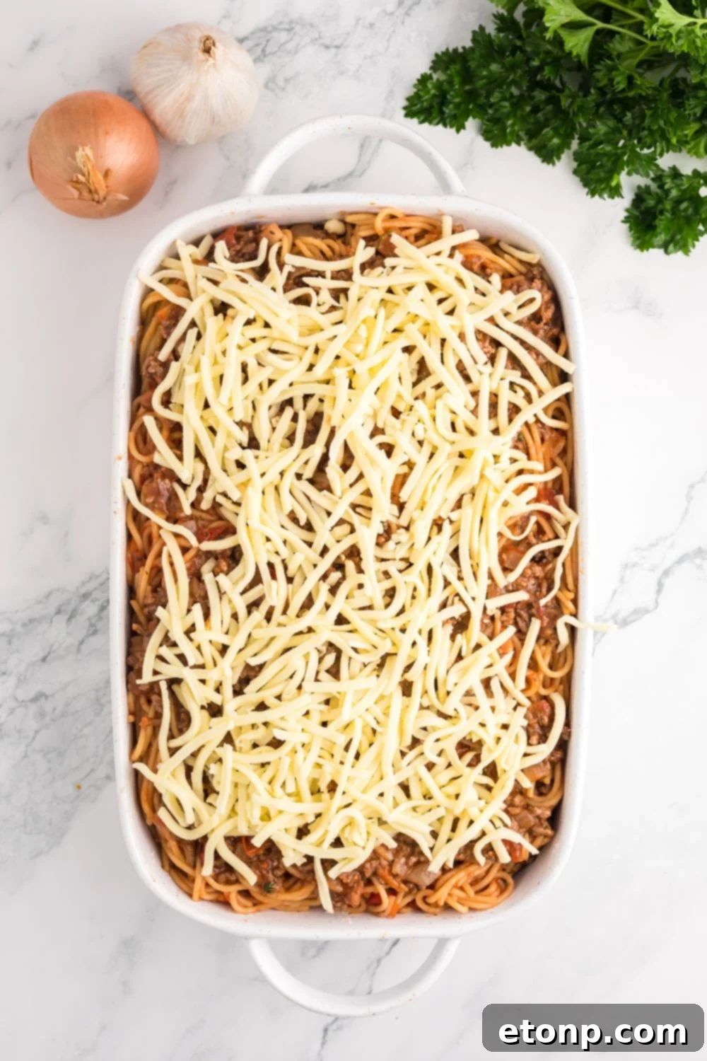 raw Million Dollar Spaghetti Casserole in a casserole pan on table waiting to be baked 
