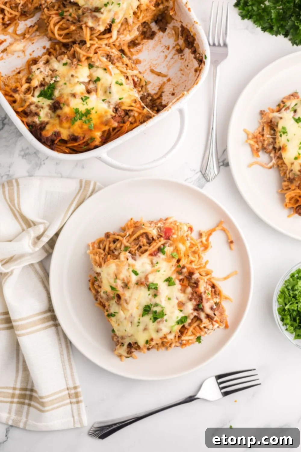 Million Dollar Spaghetti Casserole in pan and then some in plates on table 