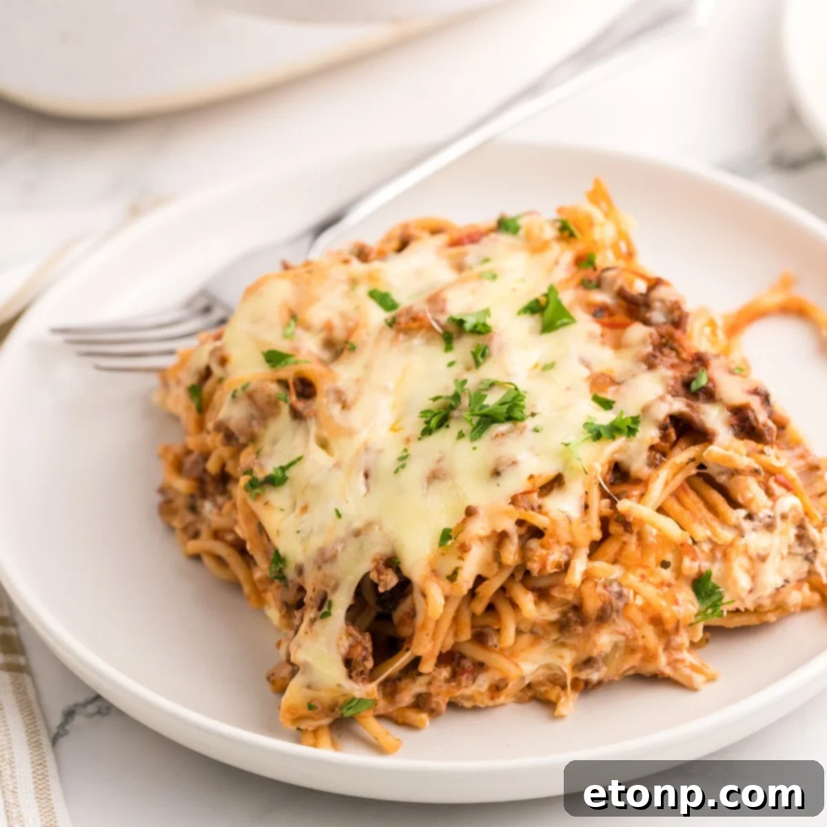 Million Dollar Spaghetti Casserole on a plate with fork on side 