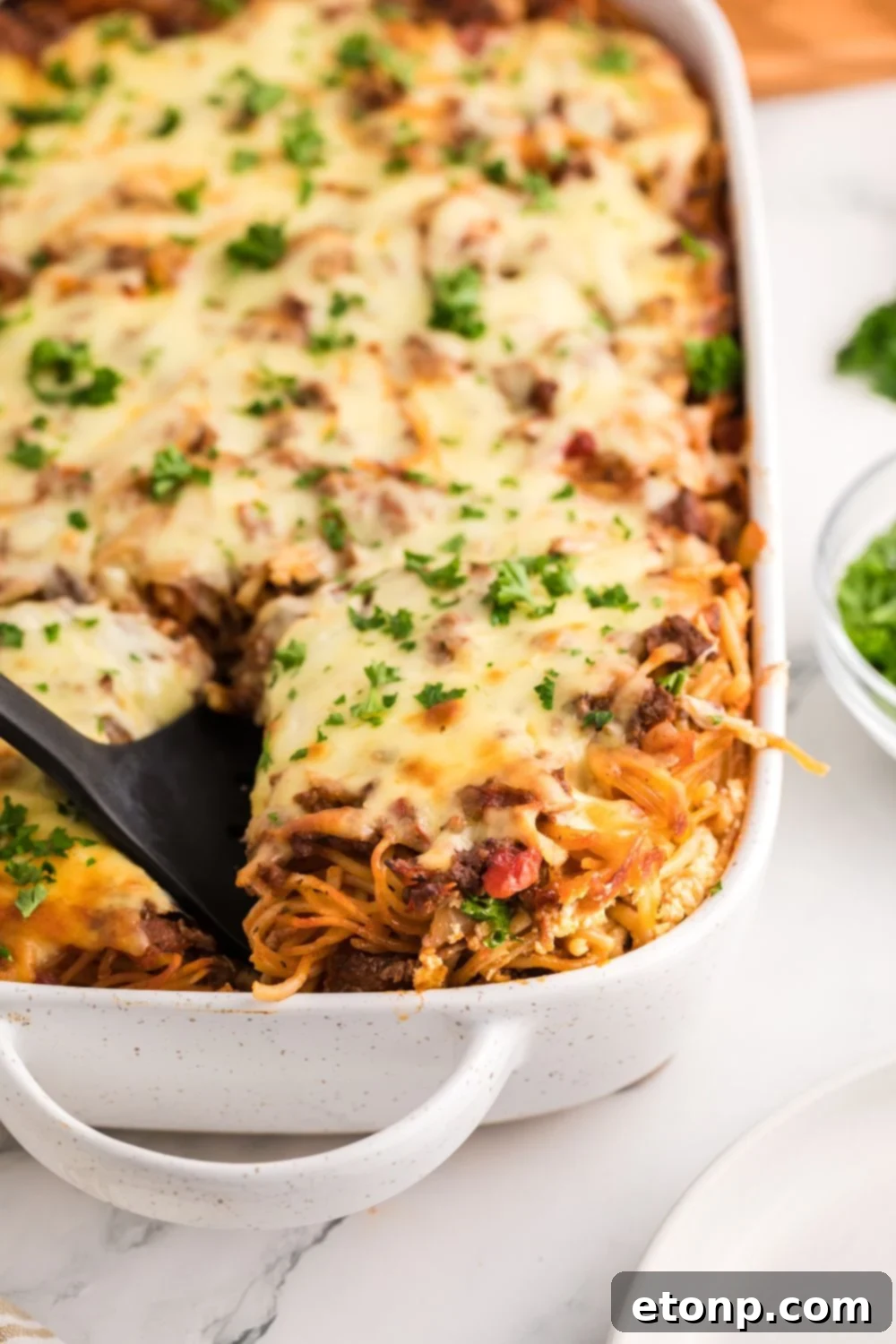 Million Dollar Spaghetti Casserole in a pan lifting some up with spatula 