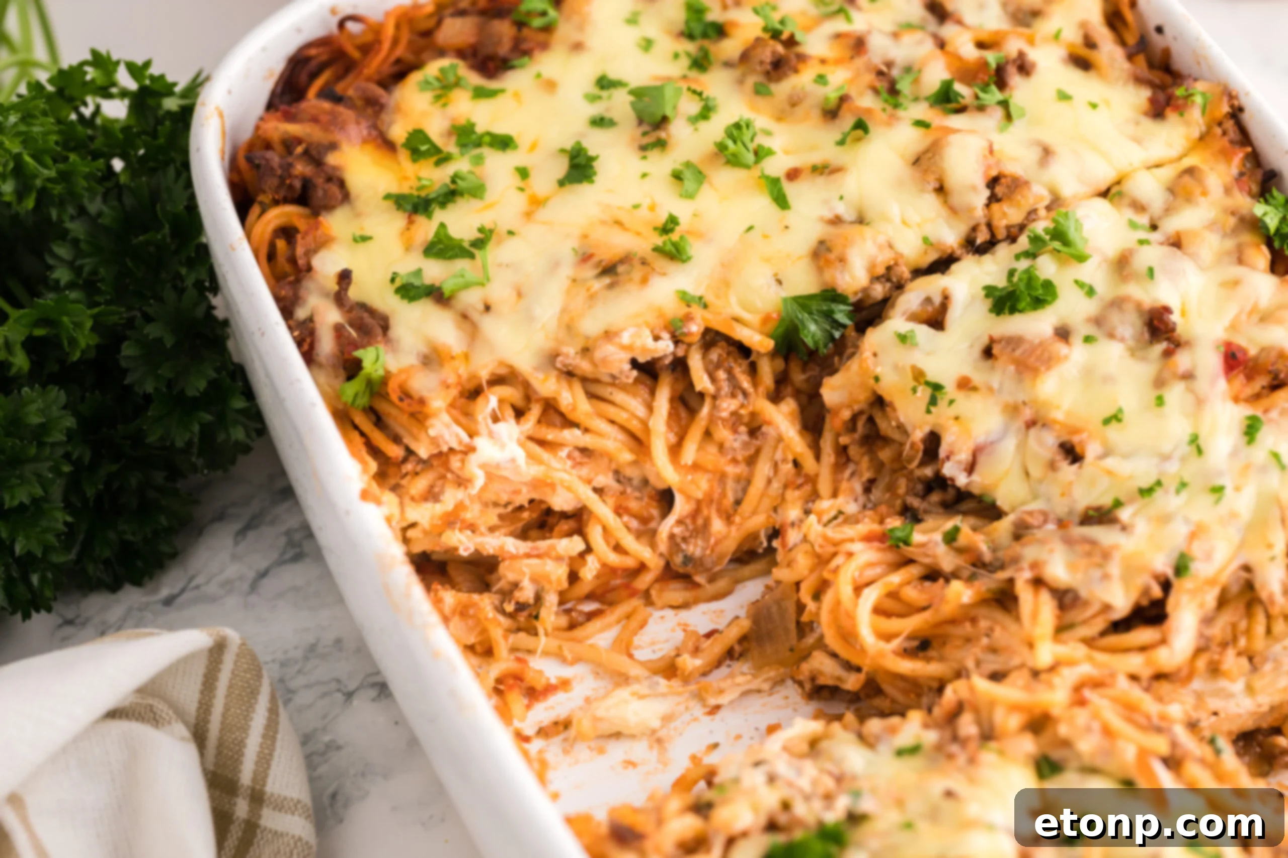 Million Dollar Spaghetti Casserole in a white baking dish with a couple slices removed 