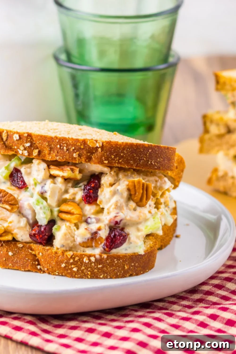 Thanksgiving Turkey Salad sandwich on white plate sitting on table with green glasses behind it on table 
