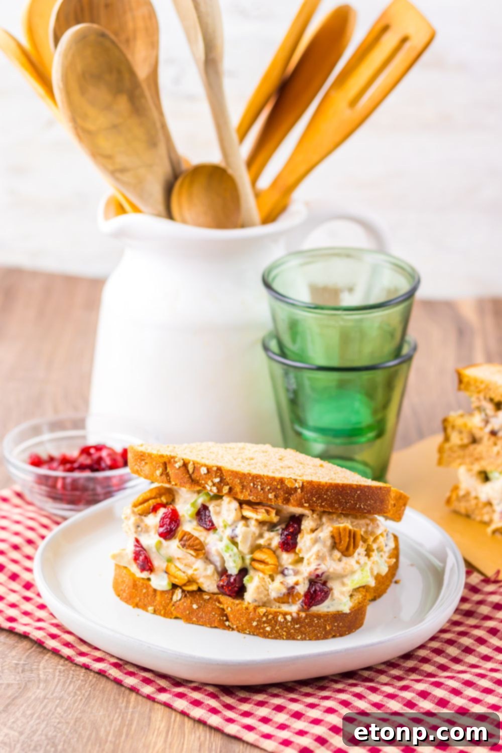 Thanksgiving Turkey Salad sandwich on table with glasses to side, and a container with spatulas and such inside 