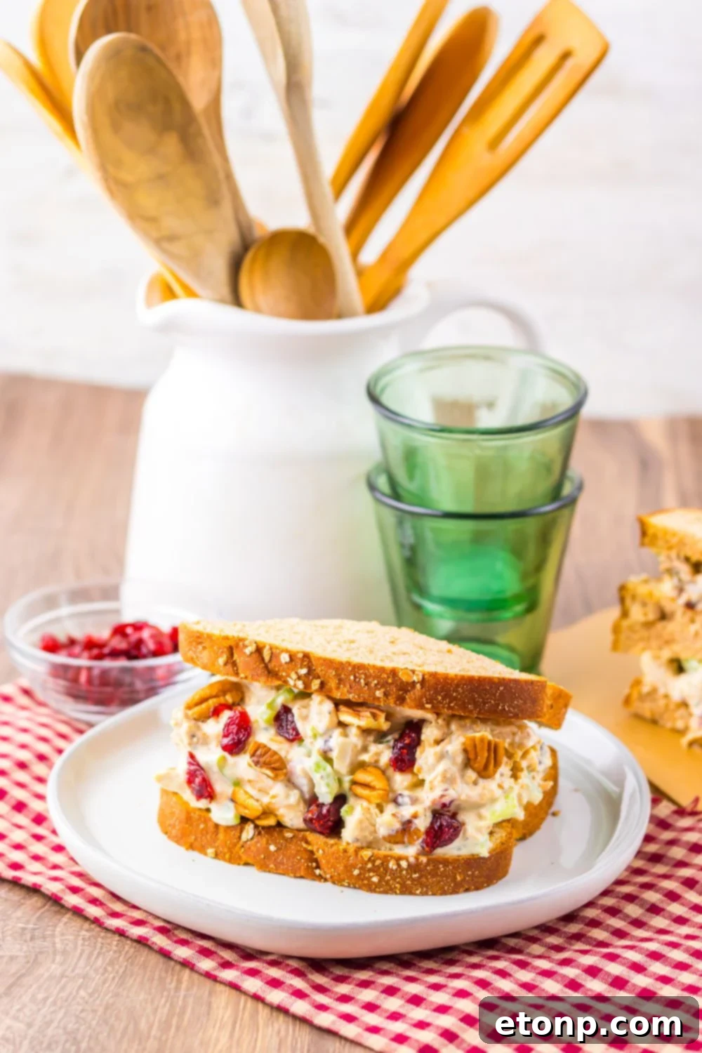 Thanksgiving Turkey Salad on plate with bread, and glasses stacked behind plate with another sandwich to the side 