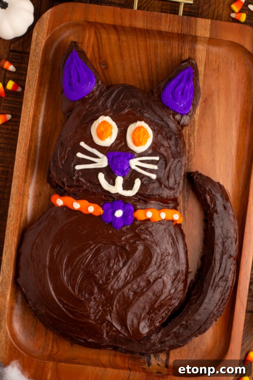 A side view of the Easy Halloween Black Cat Cut Out Cake, beautifully presented on a serving tray with candy corn accents around it.