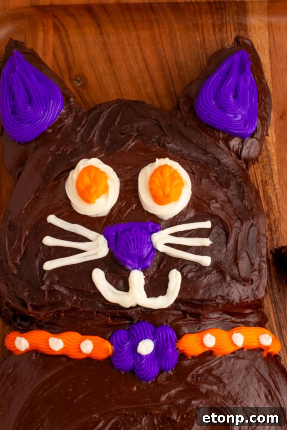 A charming close-up of the Halloween black cat cake's face, highlighting its playful candy eyes and delicate frosting details.