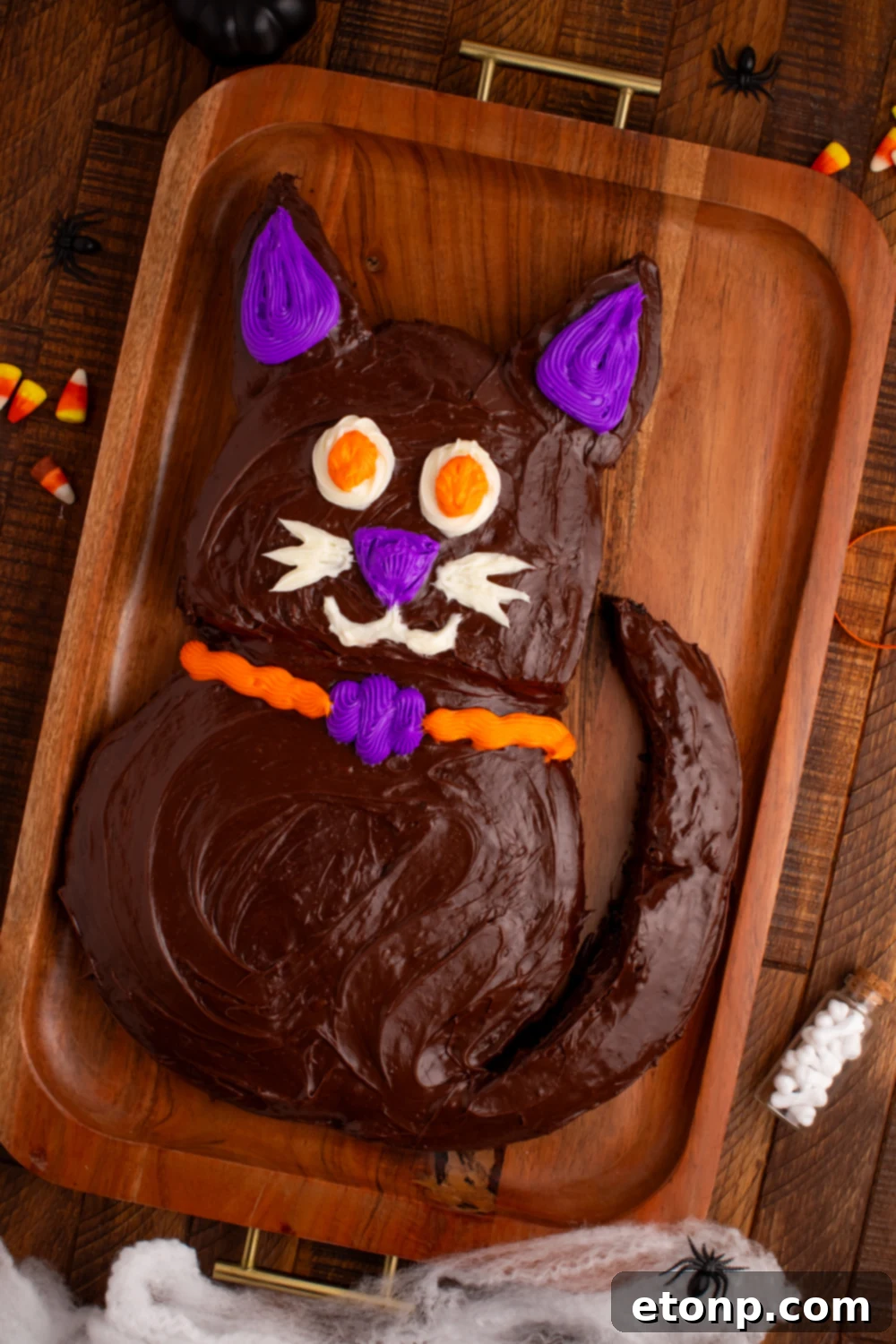Close-up of the Easy Halloween Black Cat Cut Out Cake on a serving tray with scattered candy corn, highlighting its festive appeal.