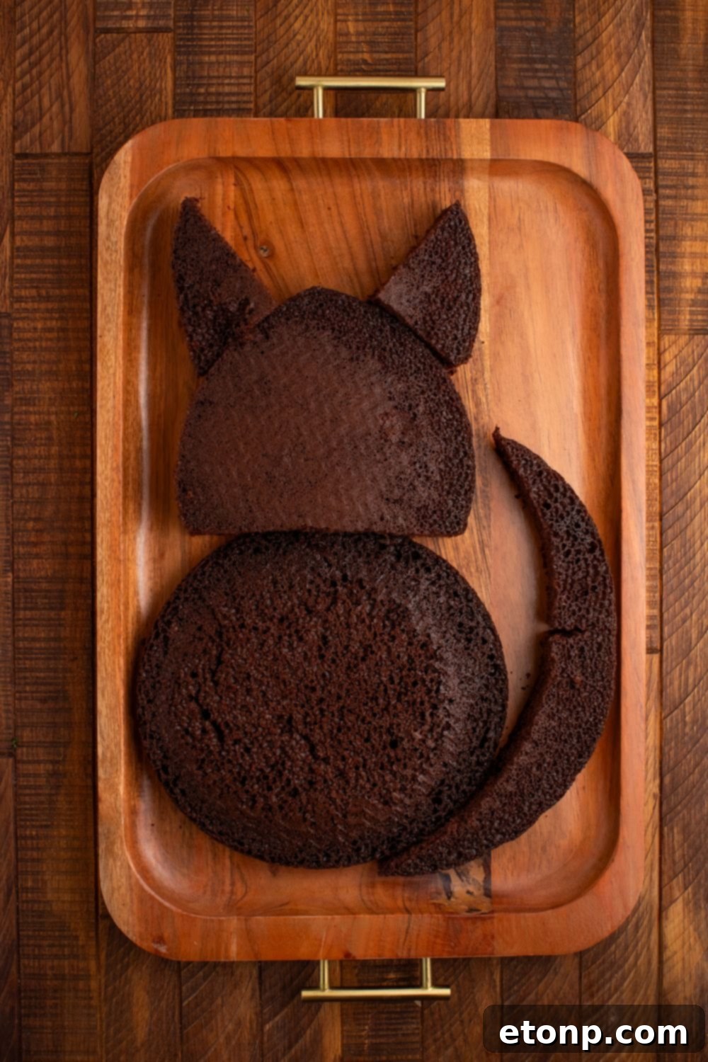 Arranged cake pieces on a serving tray, expertly shaped to resemble a charming black cat, awaiting frosting.