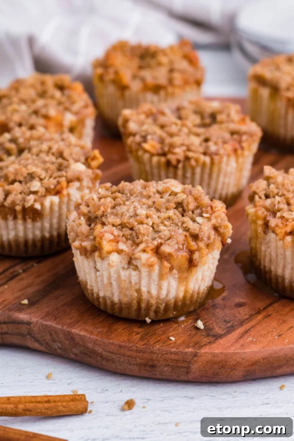 marble counter with around wooden cutting board with Apple Crisp Cheesecake Bites placed all over board with some drizzle of caramel all over the cheesecakes