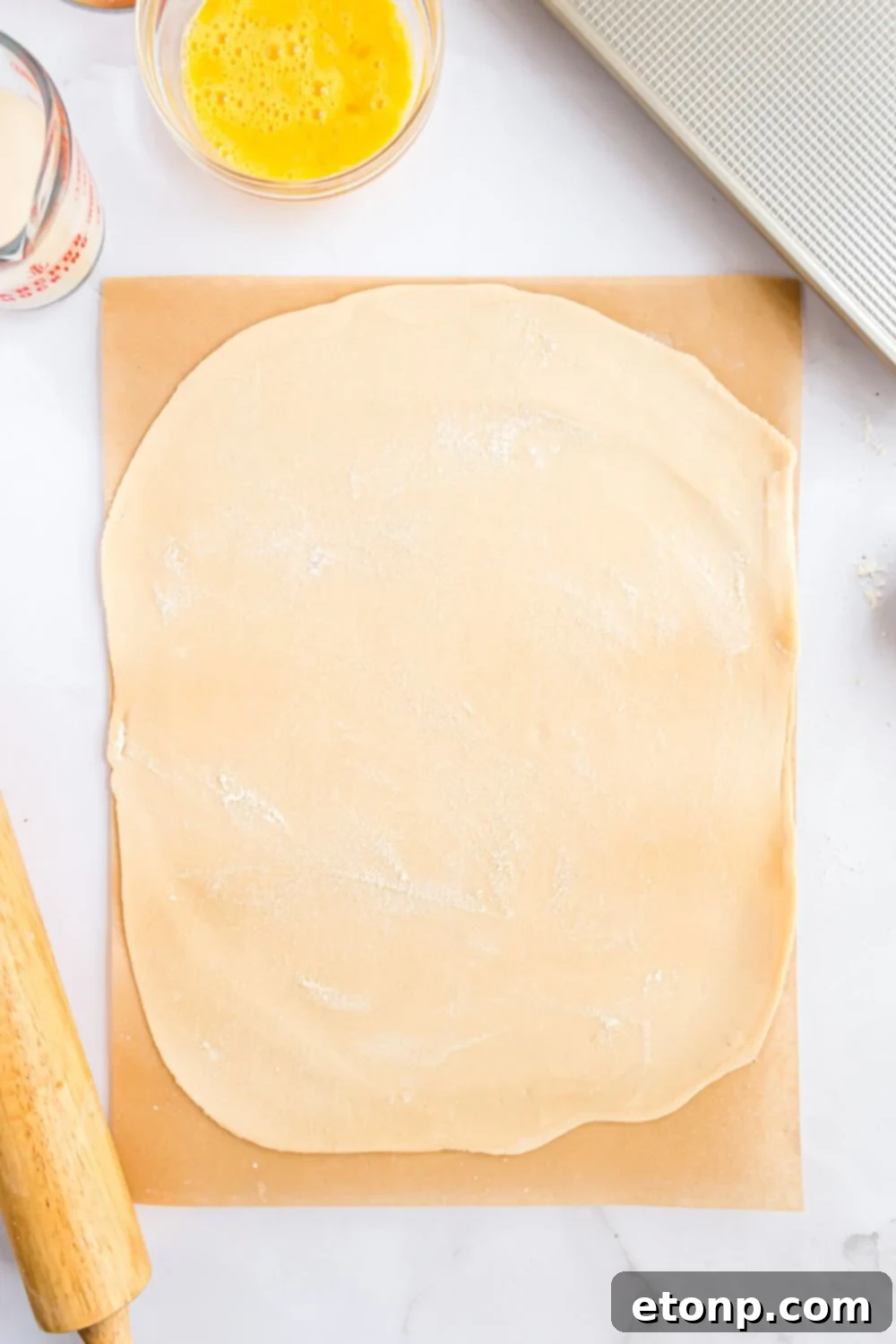 Effortless 4-Ingredient Sheet Pan Pumpkin Pie 7 pie crust sitting on a wooden cutting board being rolled out into a thin rectangle shape for making Sheet Pan Pumpkin Pie