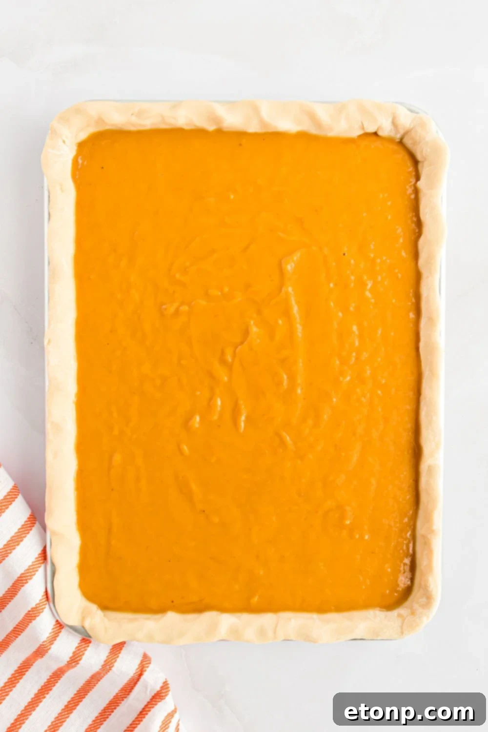 Effortless 4-Ingredient Sheet Pan Pumpkin Pie 10 overhead look down on table with a sheet pan with raw pumpkin pie in a metal sheet pan on table