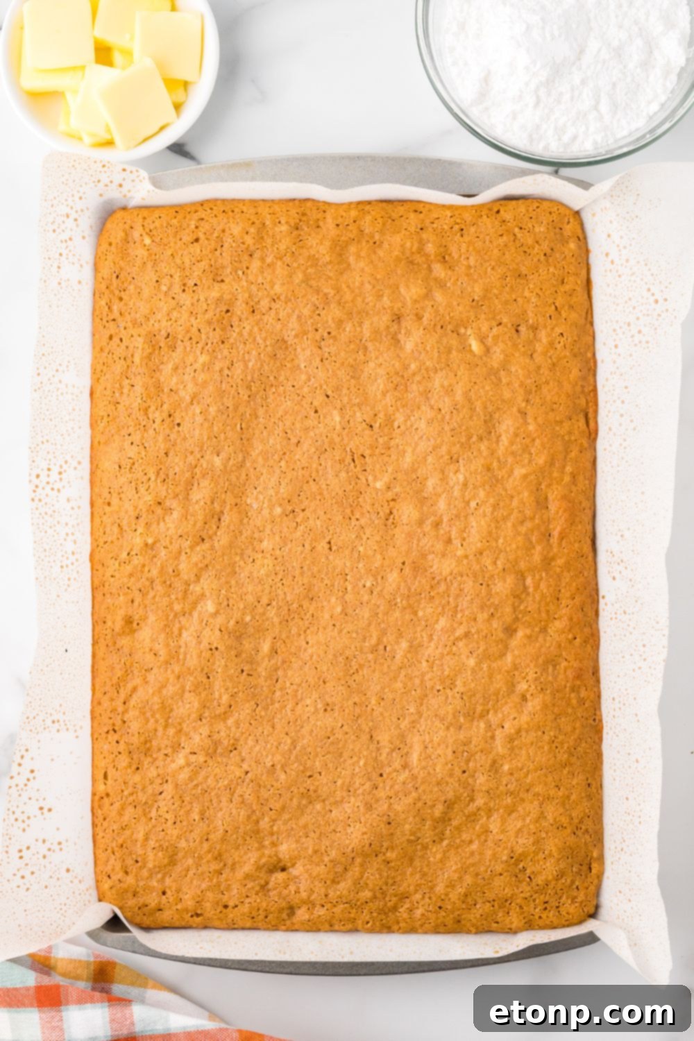 baked Pumpkin Cake Roll in a sheet pan sitting on a marble countertop