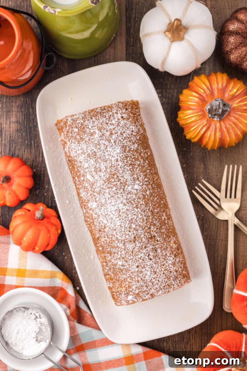 Pumpkin Cake Roll on a long platter sitting on a rustic wooden table with forks to side