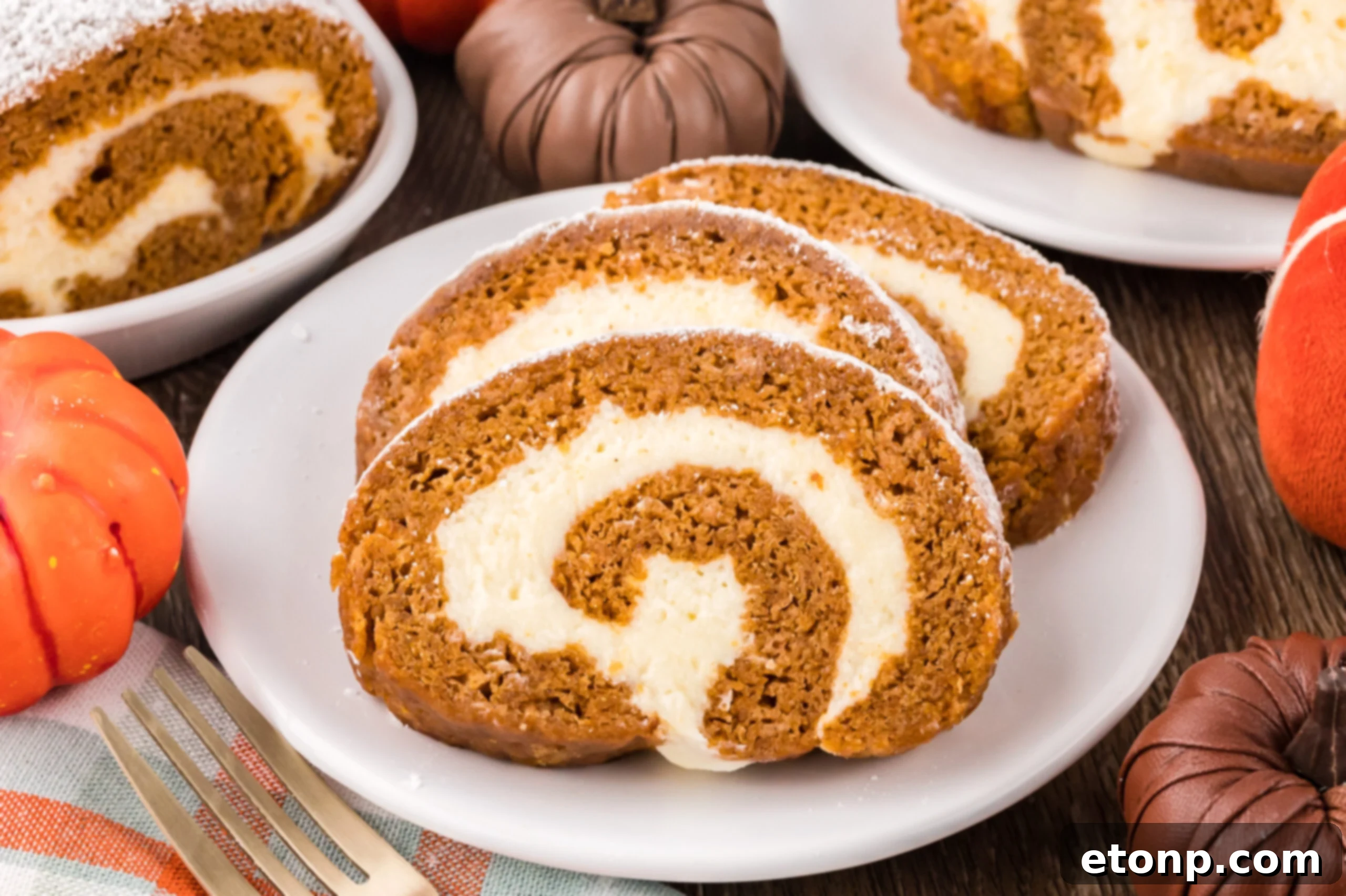 Pumpkin Cake Roll slice on a white plate on top of a dark wood table