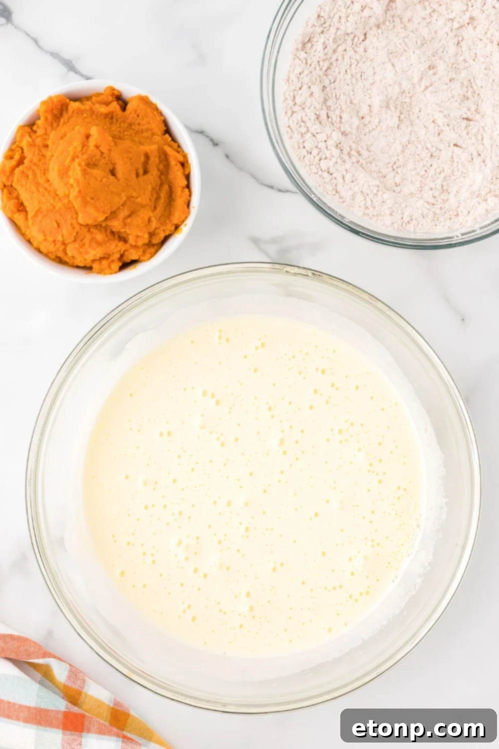wet ingredients mixed up in a glass bowl on table for making Pumpkin Cake Roll
