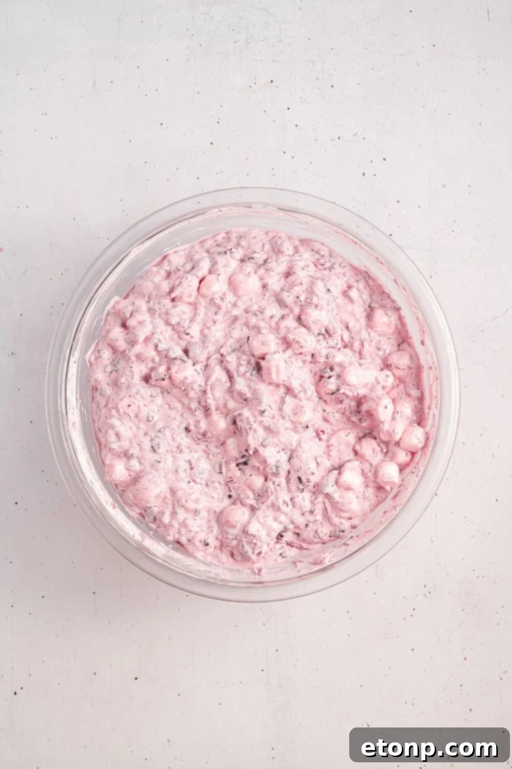 white counter with glass bowl full of Cranberry Fluff Salad mixed up