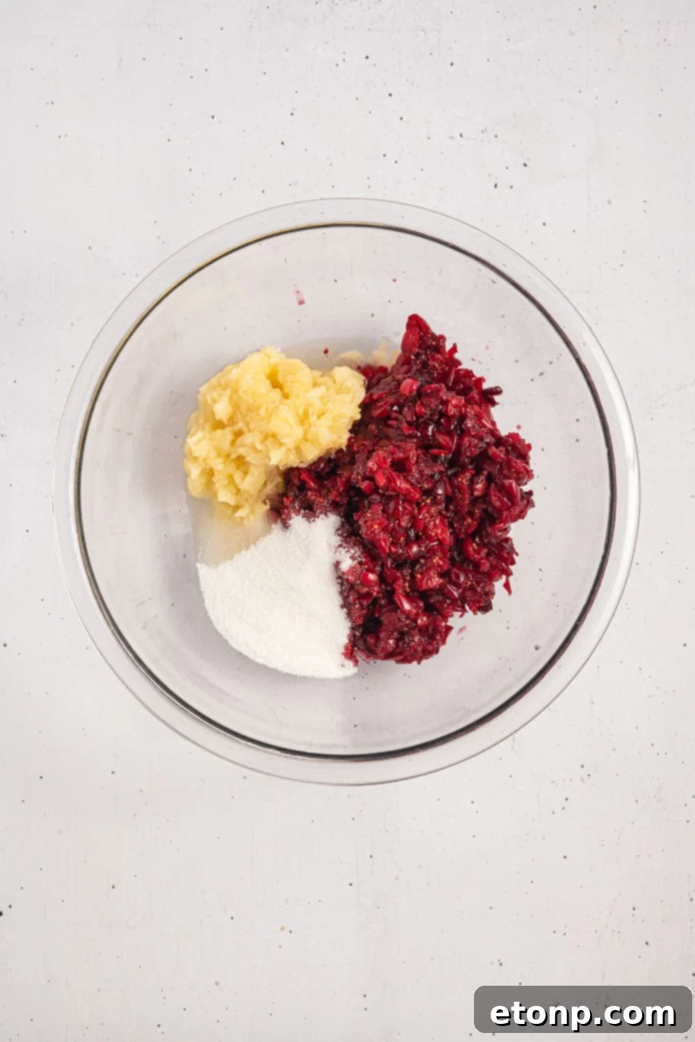 crushed cranberry mixture, sugar, and crushed pineapple in a glass bowl 