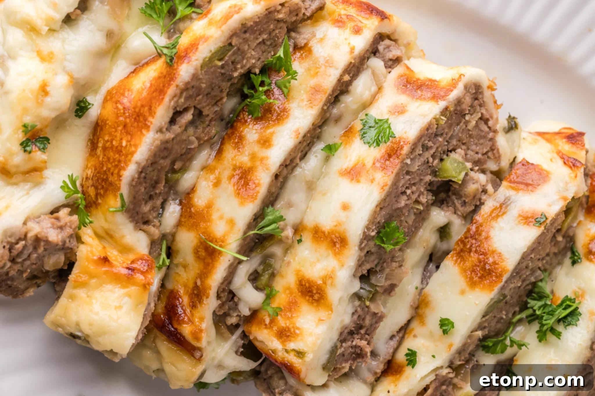 Cheesy Philly Stuffed Meatloaf with Peppers and Onions 17 Philly Cheesesteak Meatloaf sliced on a white serving plate