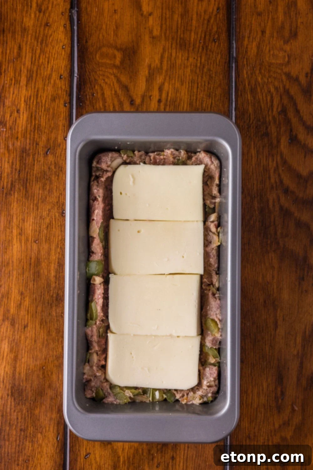 Cheesy Philly Stuffed Meatloaf with Peppers and Onions 8 half of meat topped with provolone cheese in a loaf pan to make Stuffed Philly Cheesesteak Meatloaf
