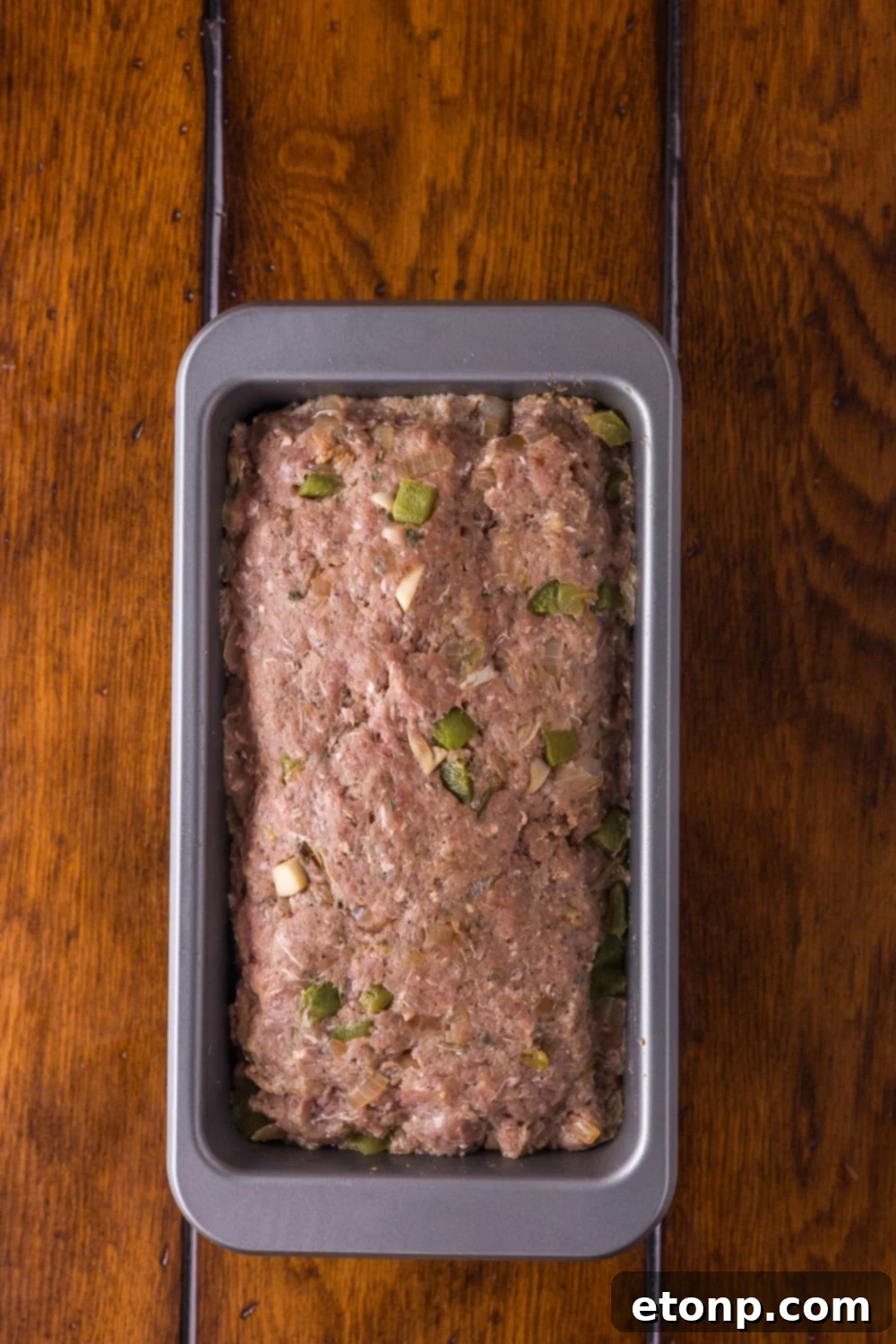 Cheesy Philly Stuffed Meatloaf with Peppers and Onions 9 raw Stuffed Philly Cheesesteak Meatloaf in a loaf pan sitting on table