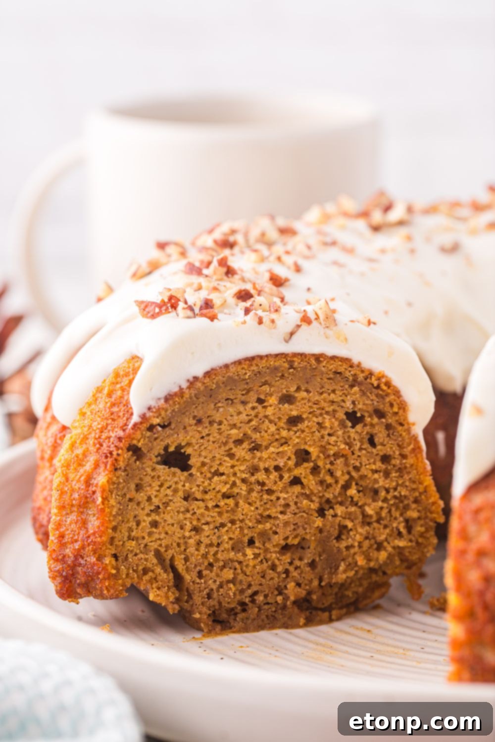 side view of a Pumpkin Bundt Cake on a cake platter with some of the cake cut out of it 