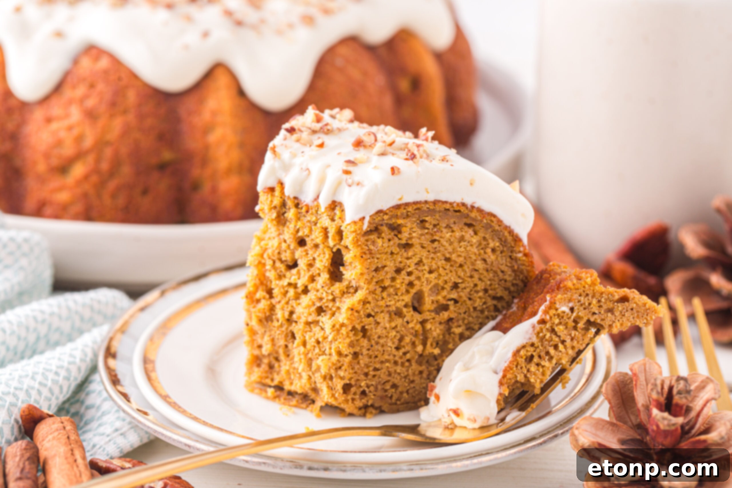 Slice of the Pumpkin Bundt Cake on a white serving plate with a fork holding a bite 