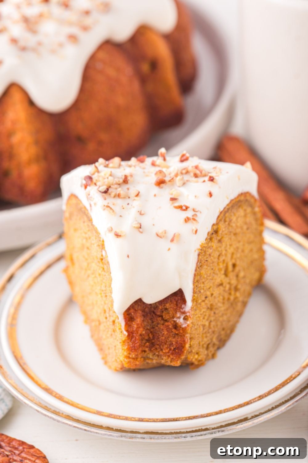 a whole Pumpkin Bundt Cake on a platter on table with a slice of cake in front 