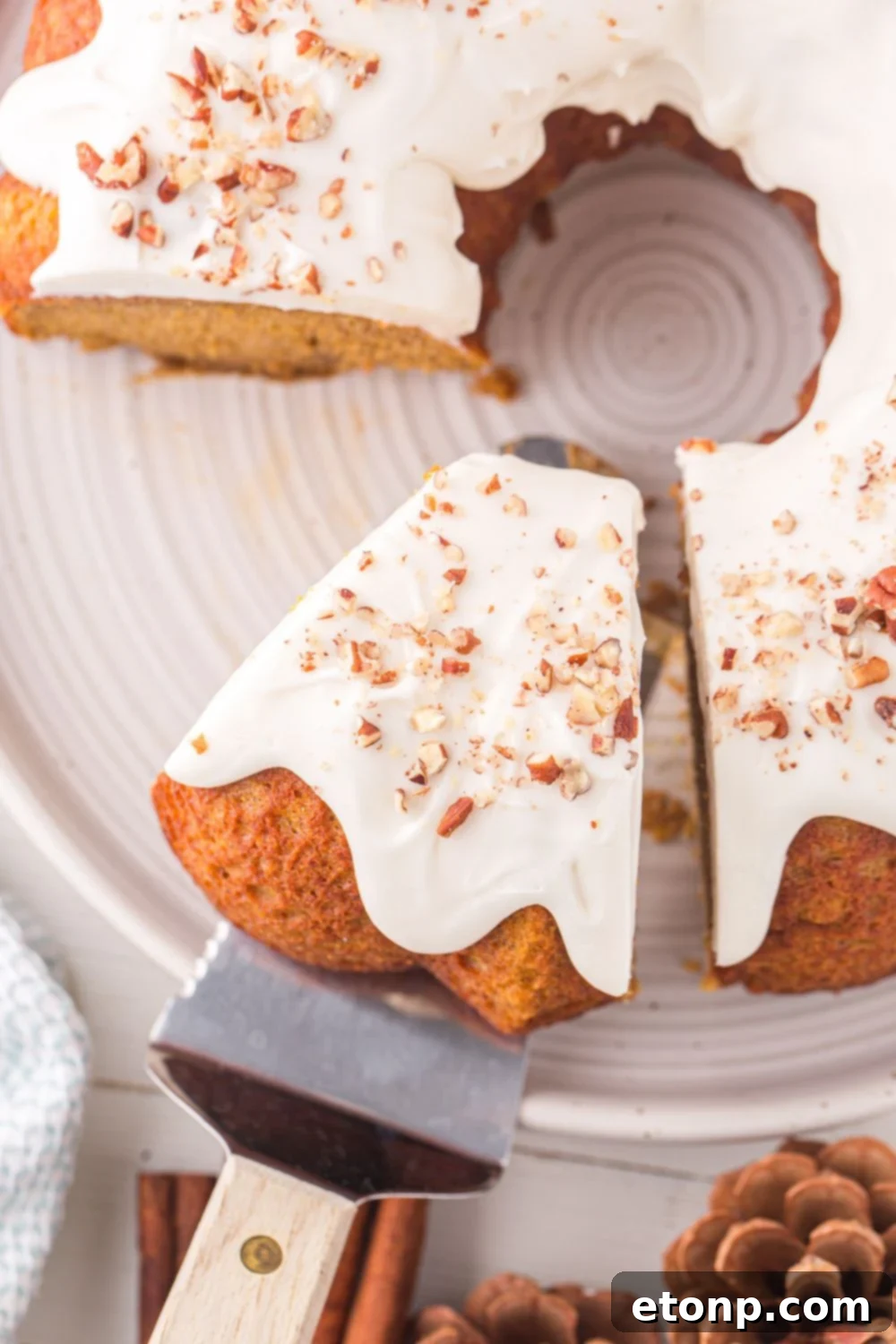 Pumpkin Bundt Cake on a white platter on table with a few slices removed and one cut on a spatula 