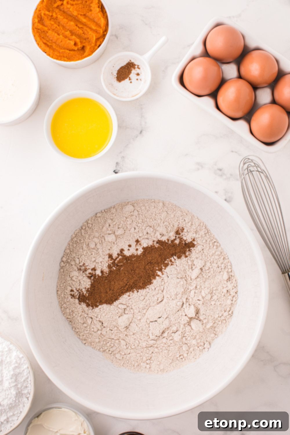 dry ingredients for making Pumpkin Bundt Cake in a white bowl on a marble counter
